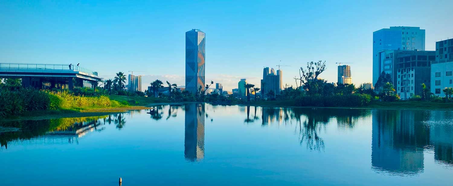 A scenic lake with towering buildings in the background at Kebena Riverside, Addis Ababa projects.